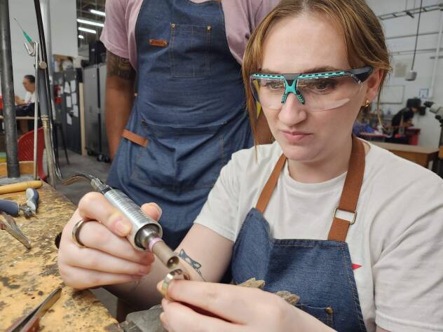 Close-up of a yellow gold wedding ring being made by the bride for the groom.