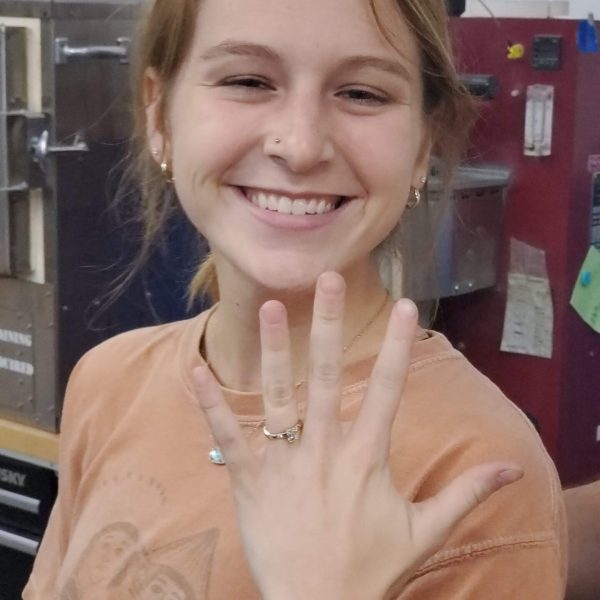 Girl who built an engagement ring in a DIY workshop holding her ring